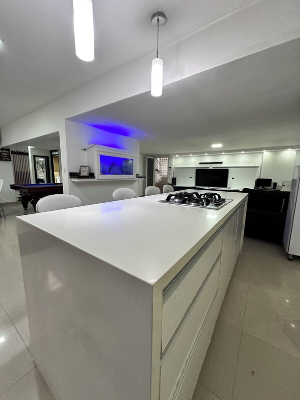A modern kitchen with a central island, built-in appliances, and a dining area with a TV.