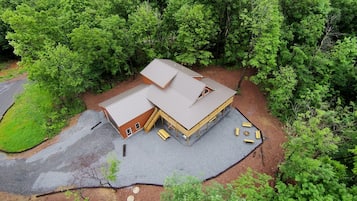 Une cabane en bois à deux étages, dotée d’un toit en pente, entourée d’une forêt dense.