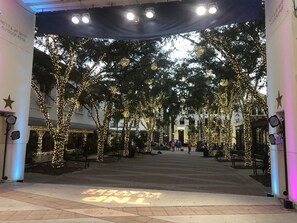 An outdoor area with trees wrapped in lights, a stage with lights, and a sign that reads "Patty & Jay Baker Outdoor Stage". - ALL 5 STAR REVIEWS for our 2Br.Cottage at Naples Bay Resort (Naples)