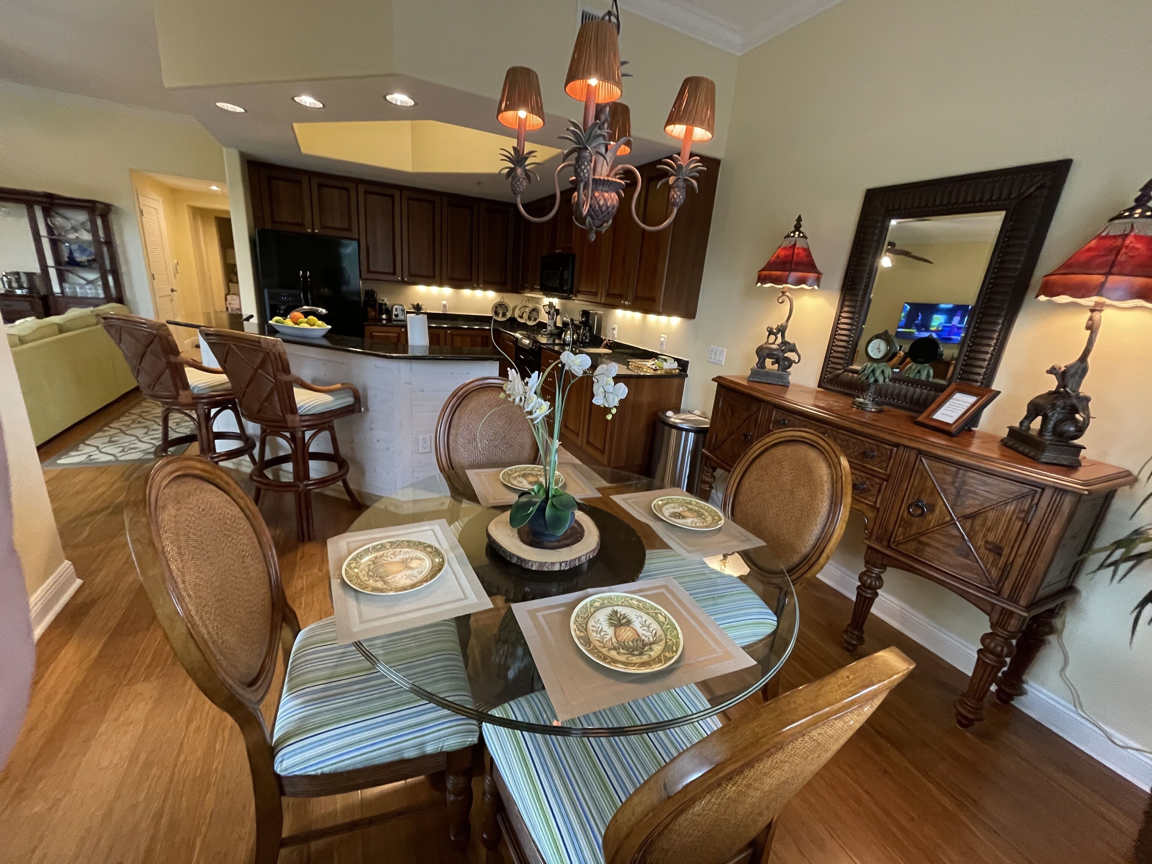 A dining area with a glass table, striped chairs, and a chandelier.