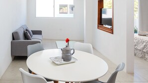 Un salon moderne avec une table à manger ronde, un canapé gris et des ventilateurs de plafond.