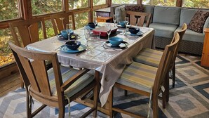 A dining area with a table set for four, surrounded by wooden chairs and a sofa. - Lakefront Spectacle In Beaver Valley / Lake Eugenia (Flesherton)