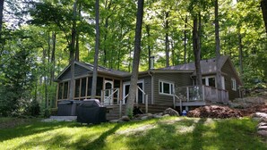 A cabin with a deck, surrounded by trees. - Lakefront Spectacle In Beaver Valley / Lake Eugenia (Flesherton)