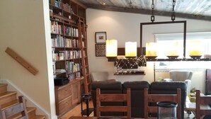 A cozy dining area with wooden furniture, a bookshelf, and a staircase leading upstairs. - Lakefront Spectacle In Beaver Valley / Lake Eugenia (Flesherton)