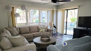Ein Wohnzimmer mit einer Couch, einem Sessel, einem Couchtisch und einem Fernseher.