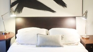 A hotel room with a large abstract painting on the wall, a neatly made bed with white linens, and two bedside lamps. - The Perfect Birmingham Get Away (Birmingham)