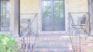 A building with a brick facade, a porch with a railing, and a set of stairs leading to a door. - The Perfect Birmingham Get Away (Birmingham)