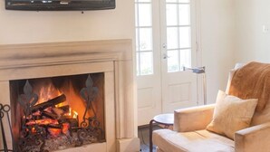 A living room with a fireplace, a sofa, a television, and a door with windows. - The Perfect Birmingham Get Away (Birmingham)