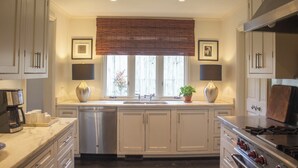 A kitchen with white cabinets, a stainless steel dishwasher, a double sink, and a stove. - The Perfect Birmingham Get Away (Birmingham)