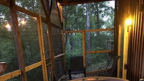 A hot tub in a wooden cabin with a view of the forest.