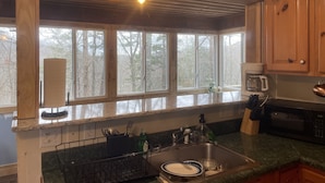 A kitchen with a large window, a sink, a coffee maker, and a microwave.