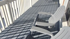 Una terrassa coberta amb cadires Adirondack i vistes a la platja.