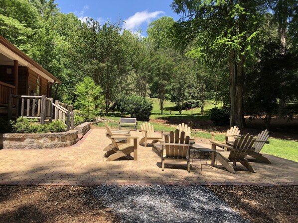 Relax in a tranquil outdoor space surrounded by lush greenery and comfortable Adirondack chairs.
