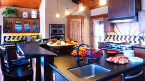 Een moderne keuken met houten balken in het plafond, roestvrijstalen apparatuur en een centraal eiland met fruit en lekkernijen.
