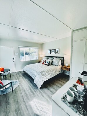 Ein modernes Schlafzimmer mit Bett, Nachttischen, Schreibtisch und Fenster.
