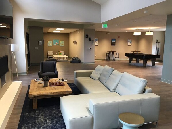 Un espace de détente moderne comprenant un canapé, une table basse et une table de billard.