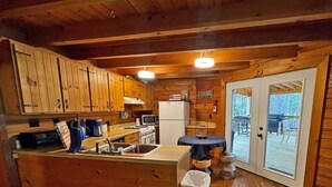 A wooden cabin kitchen with wooden cabinets, a refrigerator, a sink, and a dining table. - Log Cabin with large deck and dock in best location on the Lake! (mccormick)
