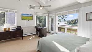 Une chambre avec un grand lit, un bureau et une vue sur un lac.