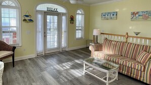 Un salon spacieux avec un canapé à rayures, une table basse et un ventilateur de plafond.