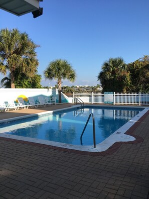 Relax by the pool surrounded by a white picket fence and lounge chairs.