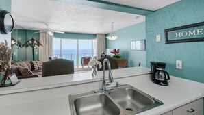 A modern kitchen with a sink, a coffee maker, and a view of the ocean through large windows. - LONG BEACH RESORT Tower 2, 13th Floor 1 Bdr!!  Awesome Views! Beautiful Unit!!! ! (Panama City Beach)
