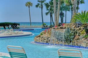 A pool with lounge chairs, a waterfall feature, and palm trees. - LONG BEACH RESORT Tower 2, 13th Floor 1 Bdr!!  Awesome Views! Beautiful Unit!!! ! (Panama City Beach)
