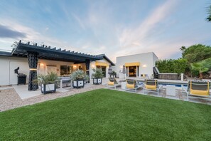 Una casa moderna con un césped cuidado, zona de estar al aire libre y piscina.