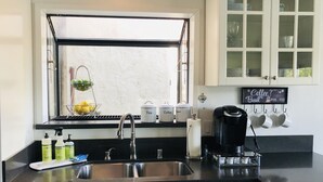 Uma cozinha com pia, janela e cesto de limões, além de um espaço para café.