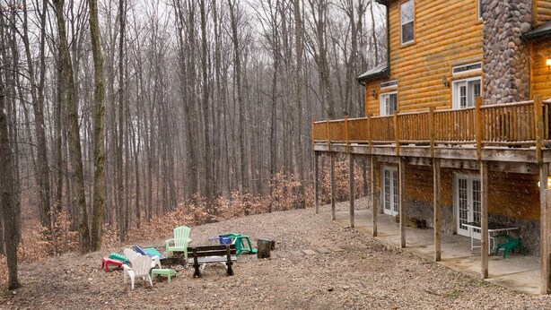 Eine Blockhütte mit Balkon, Sitzgelegenheiten im Freien und einer Steinmauer.