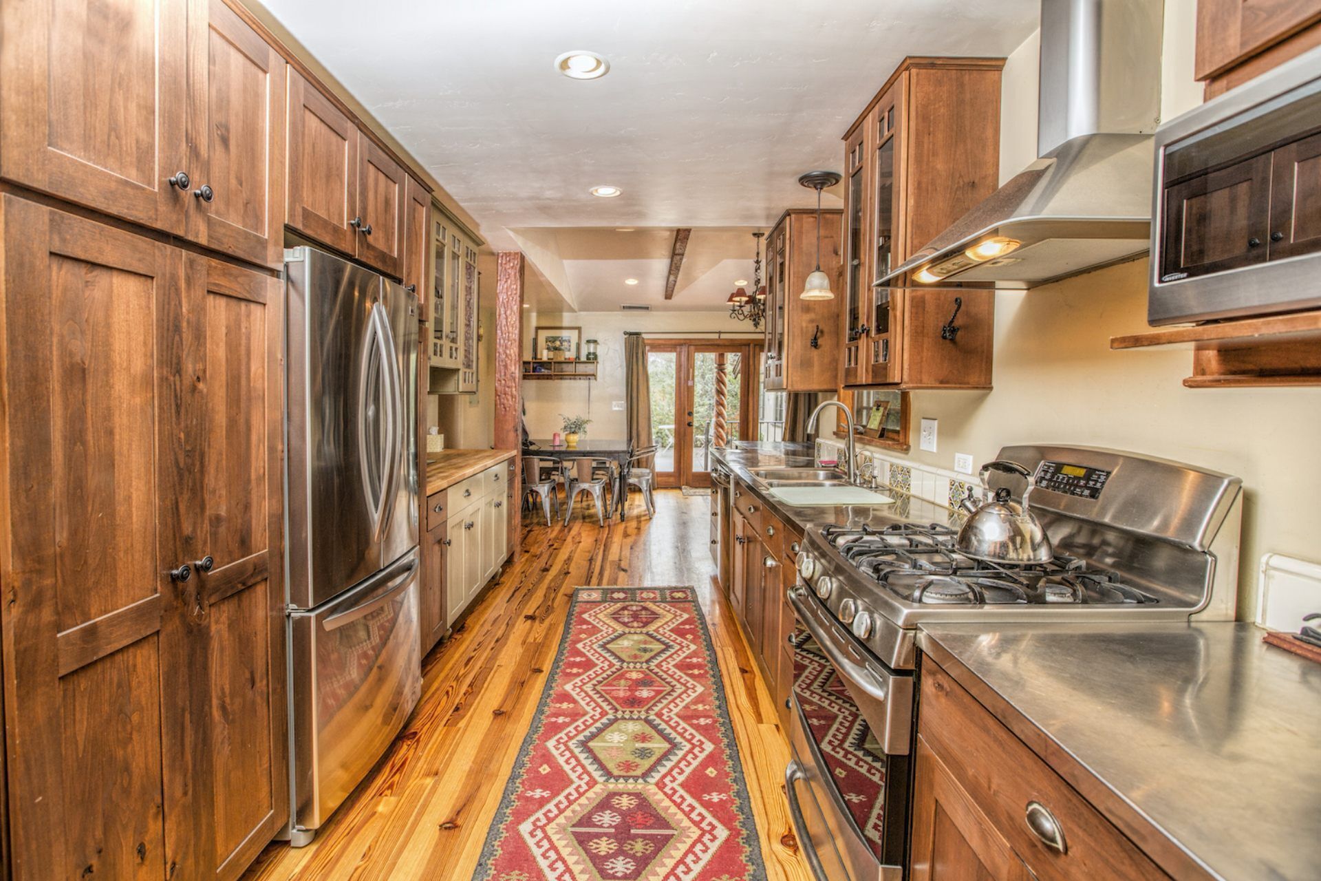 A kitchen with wooden cabinets, stainless steel appliances, and a patterned rug.