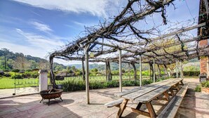 An outdoor seating area with wooden benches and a wrought iron table. - Gorgeous Rustic Ranch House & Farm Stay on 955 acre Ranch & Berry Farm-Sleeps 15 (Gaviota)