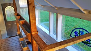 Una scala in legno conduce a un balcone da cui si vede un giardino.