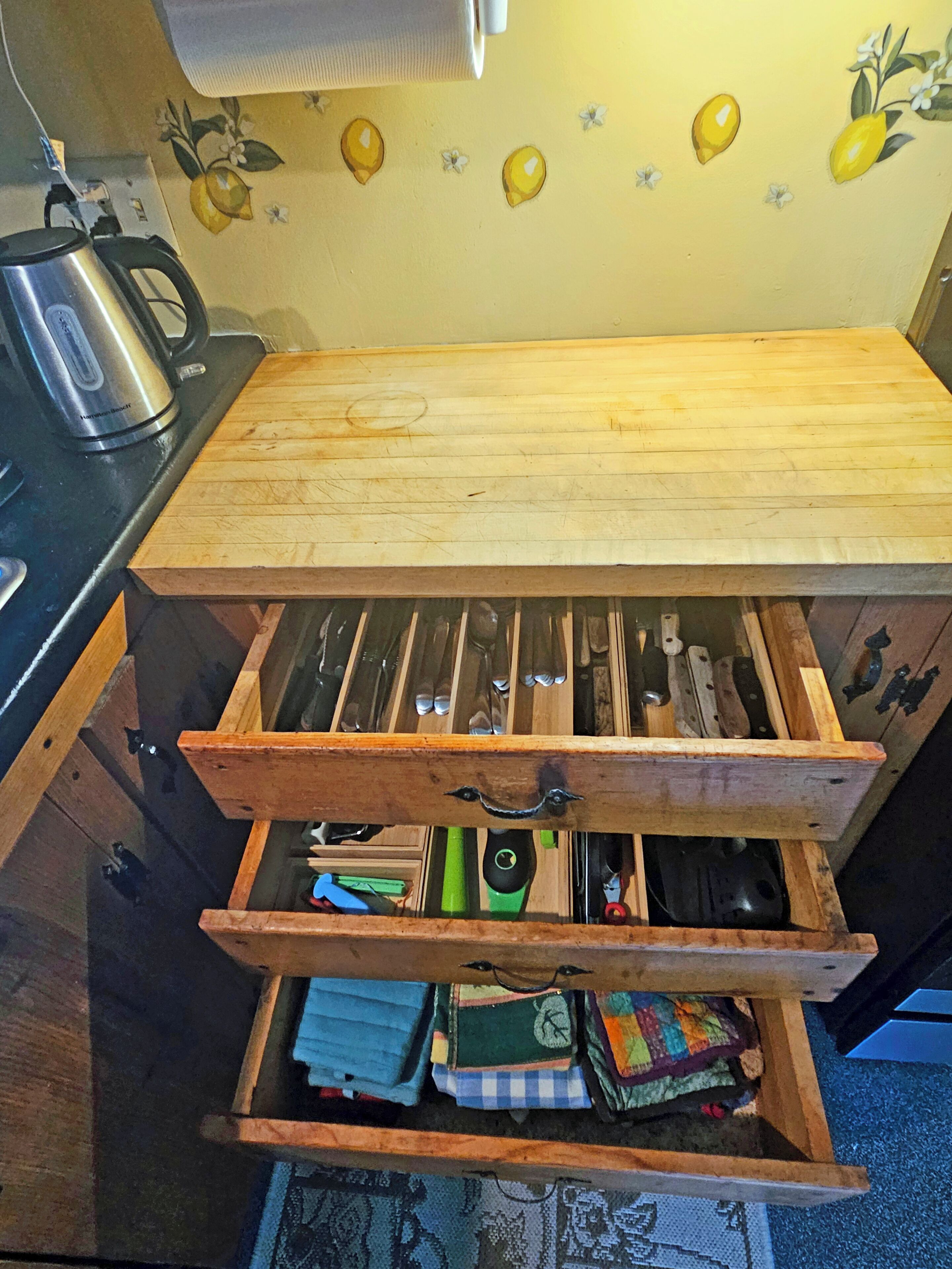 A kitchen with a wooden countertop, a kettle, and a knife block.