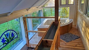 Una terrazza in legno con vasca idromassaggio e scivolo di legno.
