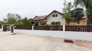 Kaksikerroksinen talo, jonka ulkoseinät ovat valkoiset, katto ruskea ja ympärillä on puinen aita.
