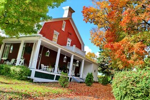 Ein rotes Haus im Kolonialstil mit einer Veranda, weißen Säulen und hängenden Laternen.
