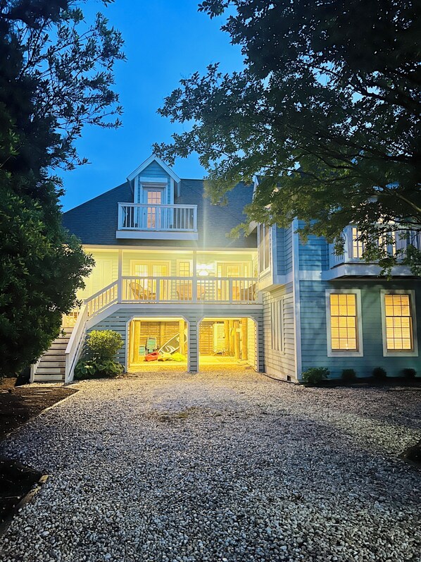 A two-story house with a balcony, a driveway, and a gravel path leading to the entrance.