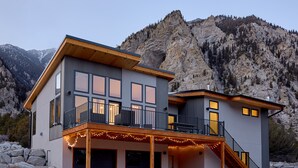 Ein modernes, zweistöckiges Haus mit Balkon, überdachter Veranda und einer Treppe, die zum oberen Stockwerk führt.