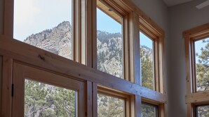 Ein Zimmer mit großen Fenstern und Blick auf eine gebirgige Landschaft.
