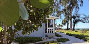 Un petit bâtiment d’un seul étage, doté d’une porte en verre, entouré de verdure et bordé d’un chemin de sable.