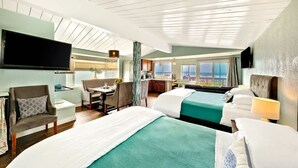 Ein Hotelzimmer mit zwei Betten, einer Essecke, einem Fernseher und Meerblick.