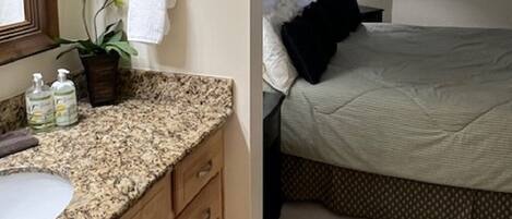 A bathroom with a granite countertop, wooden cabinet, and a large mirror.