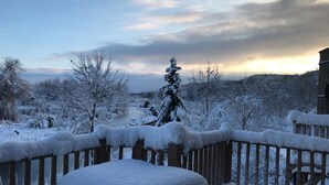 Un balcone innevato con vista su un fiume e alberi.