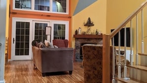 Un ampio soggiorno con soffitto alto, una scala e un camino.