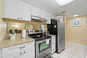 A kitchen with white cabinets, a black refrigerator, a stove, and a microwave. - GULF HOUSE #103, GREAT LOCATION, BEACH FRONT, 1ST FLOOR (Gulf Shores)