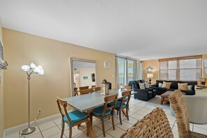A living room with a sofa, a dining table with chairs, and a lamp. - GULF HOUSE #103, GREAT LOCATION, BEACH FRONT, 1ST FLOOR (Gulf Shores)