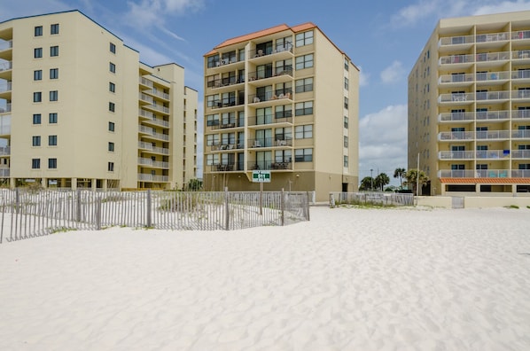 A beachfront hotel with multiple floors, balconies, and a sandy beach area.