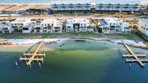 Un hotel costero con varias edificaciones blancas, un muelle y una vista despejada del océano.