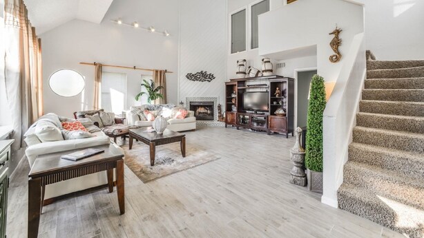 A spacious living room with a fireplace, a staircase, and a large TV. - Almost Beachfront- Beautiful Pirates Beach home- Sleeps 14-Steps to beach!! (Galveston)