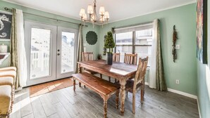 A dining area with a wooden table and chairs, a chandelier, and a potted plant. - Almost Beachfront- Beautiful Pirates Beach home- Sleeps 14-Steps to beach!! (Galveston)